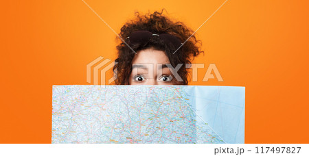 African American woman is shown with her eyes wide open, intensely examining a map in her hands, panorama 117497827