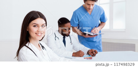 Team of doctors having meeting in medical office, woman looking at camera Team of doctors having meeting in medical office, woman looking at camera 117498329