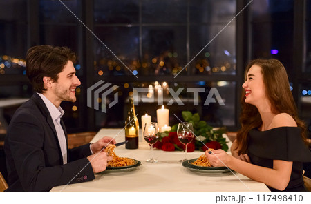 Loving beautiful young couple in a restaurant celebrating anniversary. Romantic dinner on Valentine day concept Loving beautiful young couple in a restaurant celebrating anniversary. Romantic dinner on Valentine day concept 117498410