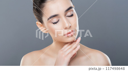 A woman with her hands resting on her face, expressing emotions or deep in thought. She appears to be contemplative or distressed, with a thoughtful expression on her face. 117498648