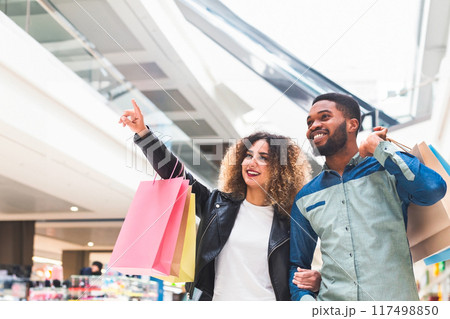 Big sale concept. Young african american couple doing shopping together in city mall, panorama 117498850
