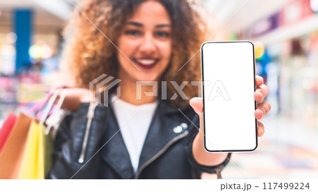 Online shopping concept. Young african woman showing cellphone screen with blank space for advertisement Online shopping concept. Young african woman showing cellphone screen with blank space for advertisement 117499224