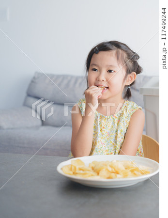 お菓子のポテトチップスを食べる子供 117499244