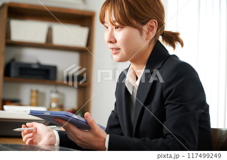 自宅でタブレットを操作するスーツの女性 自宅でタブレットを操作するスーツの女性 117499249