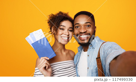African American man and woman are standing together, holding a phone out in front of them to take a selfie. They are both smiling and posing for the camera, capturing a moment together. African American man and woman are standing together, holding a phone out in front of them to take a selfie. They are both smiling and posing for the camera, capturing a moment together. 117499330