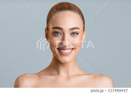 Beauty portrait. Beautiful woman with perfect smile and clean skin over grey studio background 117499457