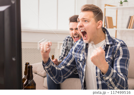 Intense excitement as two european guys cheer on their team, embodying the passion of friendship and sports enthusiasm Intense excitement as two european guys cheer on their team, embodying the passion of friendship and sports enthusiasm 117499516