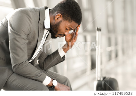 Problem with Transportation. Businessman Late for Flight, Sitting with his Luggage in Airport 117499528