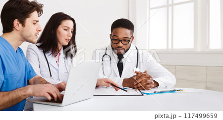 Medical Team Discussing Reports, Using Laptop in Meeting Room 117499659