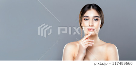 A woman without a shirt, standing with her hand covering her face. She appears distressed or contemplative, panorama with copy space 117499660