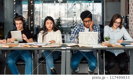 Students using different gadgets studying in university library and preparing for exams Students using different gadgets studying in university library and preparing for exams 117499833