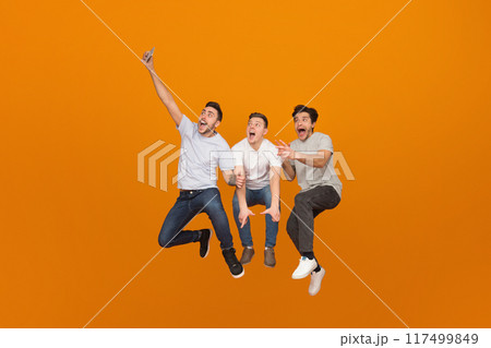 Fooling together. Men taking selfie when jumping on orange studio background 117499849
