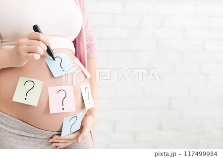 Concept of choosing baby name. Pregnant woman with question marks on paper stickers on tummy, panorama with empty space Concept of choosing baby name. Pregnant woman with question marks on paper stickers on tummy, panorama with empty space 117499984