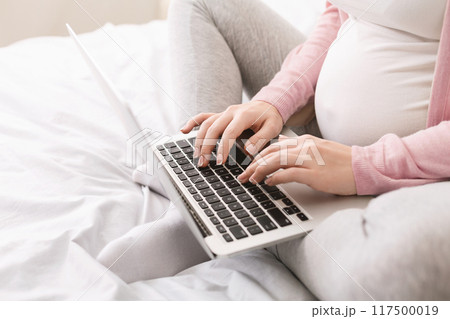 Pregnant lady using laptop, working in homeoffice or taking online education courses during maternity leave, closeup Pregnant lady using laptop, working in homeoffice or taking online education courses during maternity leave, closeup 117500019