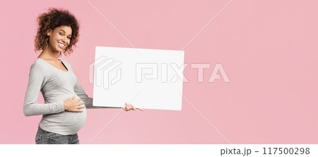 Black pregnant woman showing blank advertising board over pink studio background, free space 117500298