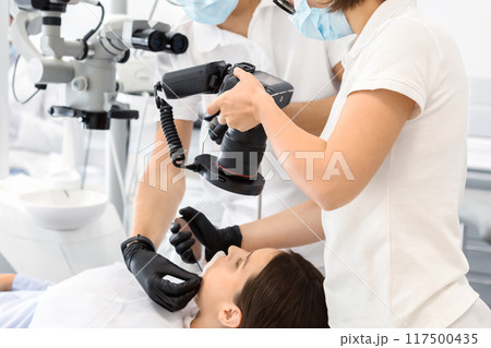 Two professional dentists taking photo of patient teeth in modern dental clinic, using camera 117500435