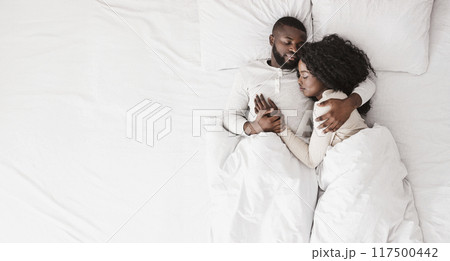 African american family couple lying and cuddling in bed, sleeping together, top view African american family couple lying and cuddling in bed, sleeping together, top view 117500442