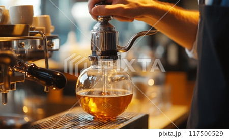 A barista skillfully brews coffee using a siphon in a warm cafe, showcasing the unique process and aroma as the drink caramelizes. 117500529