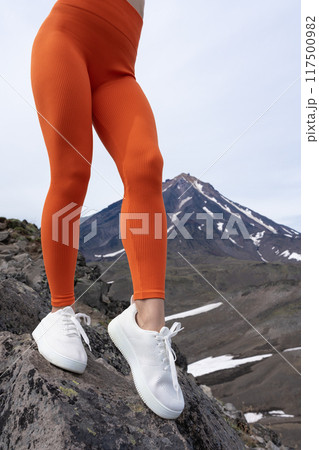 Close-up of female fitness enthusiast in leggings and white sneakers. Sensuality fitness model showing off her incredible leg workout. Athlete outdoor fitness training session in mountainous 117500982