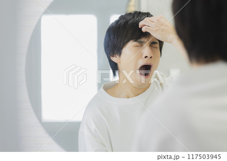 洗面所で鏡を見る若い男性 117503945