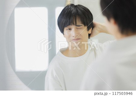 洗面所で鏡を見る若い男性 117503946
