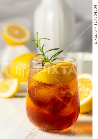 Iced tea with ice, rosemary and lemon slices on the white table. Iced tea with ice, rosemary and lemon slices on the white table. 117504304