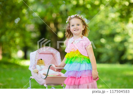 Little girl pushing a toy stoller wth doll 117504583
