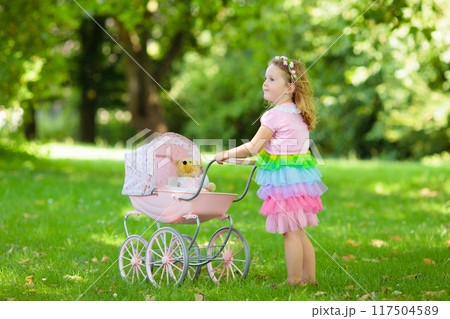 Little girl pushing a toy stoller wth doll 117504589