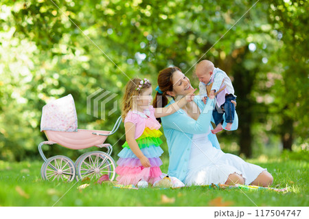 Mother and kids enjoying picnic outdoors Mother and kids enjoying picnic outdoors 117504747
