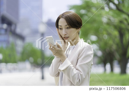 公園でコンパクトを見るミドルエイジの女性 117506806