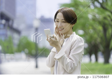 公園でコンパクトを見るミドルエイジの女性 117506807