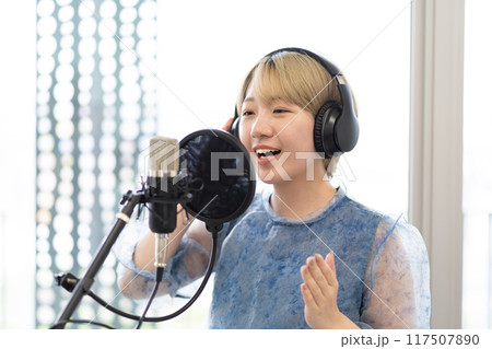 歌を歌う金髪ショートヘアの若い女性（コンデンサーマイク、録音、ボーカル、ナレーター） 117507890