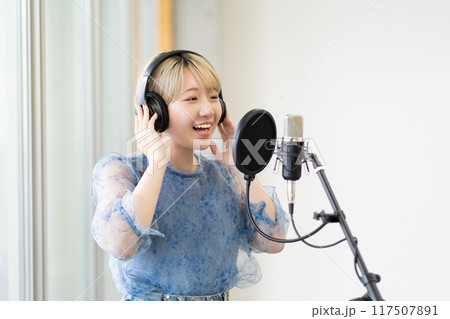 歌を歌う金髪ショートヘアの若い女性（コンデンサーマイク、録音、ボーカル、ナレーター） 117507891