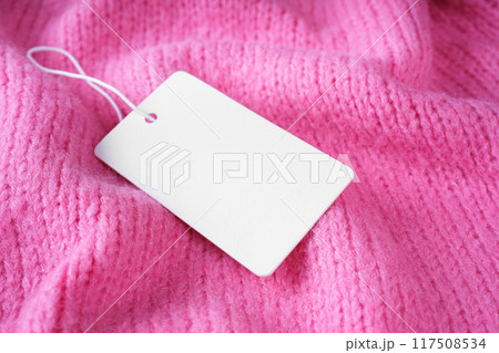Template of blank clothing label, price tag on pink crumpled knitted sweater background Template of blank clothing label, price tag on pink crumpled knitted sweater background 117508534