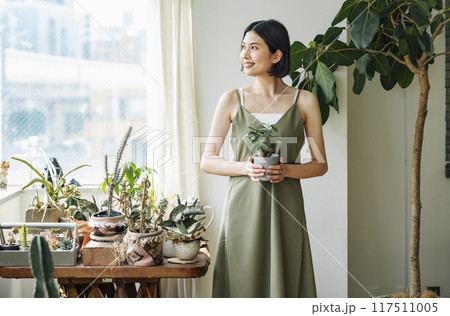 部屋で観葉植物を持つ女性 117511005