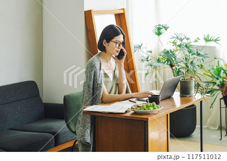自宅でスマホで話す女性 117511012