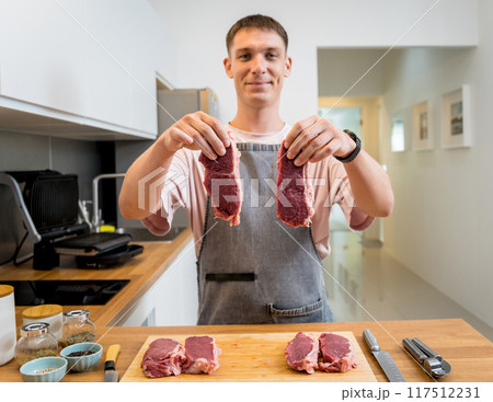 Raw fillet beef meat for steaks on the home electric grill Raw fillet beef meat for steaks on the home electric grill 117512231