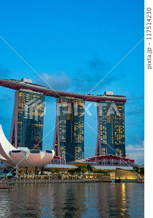 A stunning view of Sands Sky Park atop Marina Bay Sands in Singapore, captured during twilight. The deep blue sky at dusk creates a romantic and beautiful backdrop. 117514230