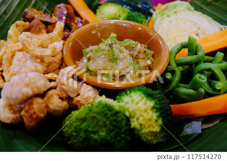 Northern Thai spicy sausage with chilli dips and deep fried pork skins and vegetable on banana leaf. Tradition food in Thailand Northern Thai spicy sausage with chilli dips and deep fried pork skins and vegetable on banana leaf. Tradition food in Thailand 117514270