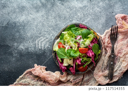 Fresh salad with lettuce, tomato, cucumber and red onion on dark background 117514355