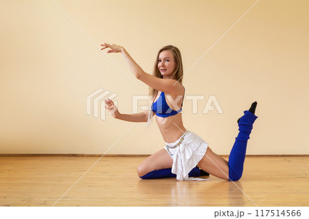 Young woman dancing belly dance in a dance studio on a beige background 117514566