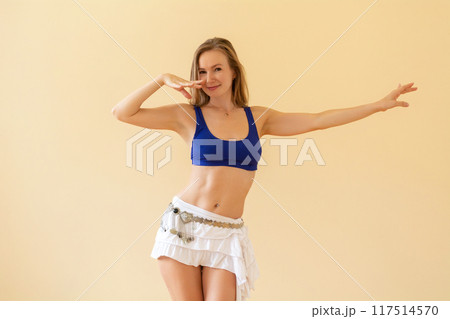 Young woman dancing belly dance in a dance studio on a beige background Young woman dancing belly dance in a dance studio on a beige background 117514570