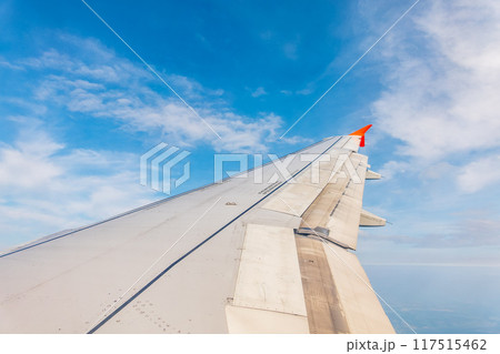 View from the airplane window at a beautiful cloudy sky and the airplane wing 117515462