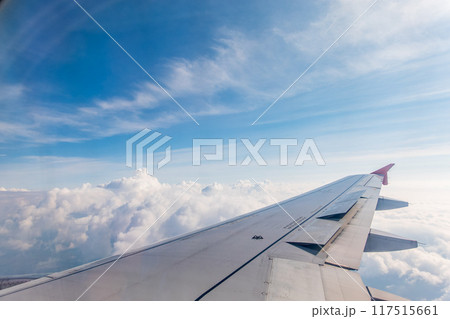 View from the airplane window at a beautiful cloudy sky and the airplane wing View from the airplane window at a beautiful cloudy sky and the airplane wing 117515661