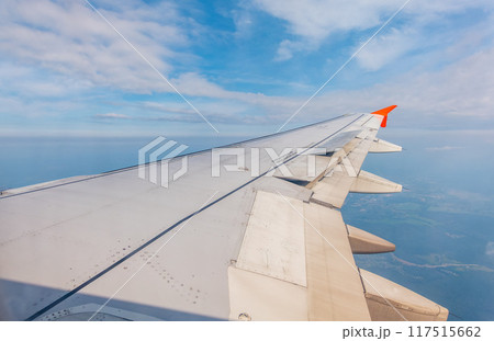 View from the airplane window at a beautiful cloudy sky and the airplane wing 117515662