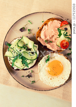 Assortment of sandwiches, white bread, fried egg, cream cheese and cucumber, capelin caviar, sesame bun, breakfast, on a white table, no people, 117515910