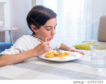 Boy eating meal at table 117517315