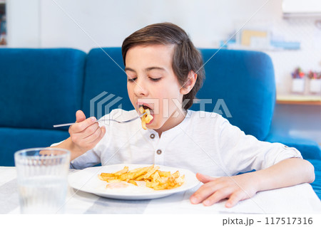 Boy eating meal at table Boy eating meal at table 117517316