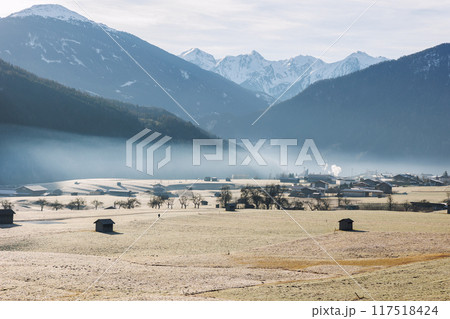 Scenic picturesque landscape view many small little wooden log alpine hut on alpine austrian meadow Alps with mountain peaks sky background foggy morning. Serene peaceful solitude nature countryside 117518424