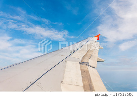 View from the airplane window at a beautiful cloudy sky and the airplane wing View from the airplane window at a beautiful cloudy sky and the airplane wing 117518506